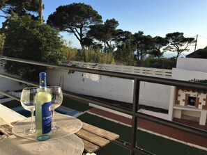 A terrace with a table, a bottle of Casalguado wine, and a glass on a woven mat. - Casa Capuchos. Close to Lisbon with Ocean View (Caparica)