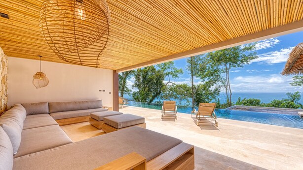 Ein moderner Außenbereich mit Pool, Holzmöbeln und Meerblick.