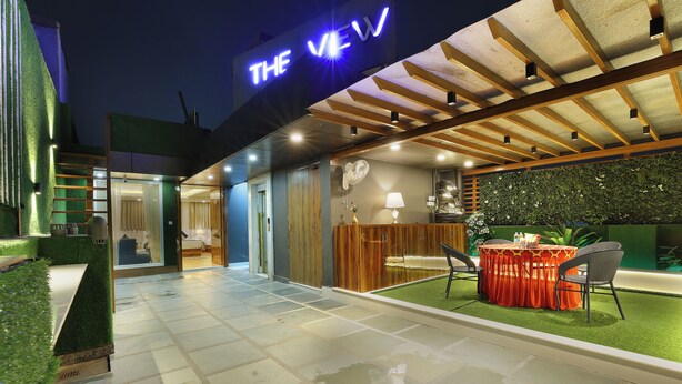 A modern hotel exterior with a sign reading "THE VIEW," a covered outdoor seating area, and a well-lit entrance. - A Boutique Hotel View (New Delhi)
