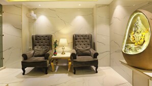 A modern room with two leather armchairs, a small table with a lamp, and a decorative statue. - A Boutique Hotel View (New Delhi)