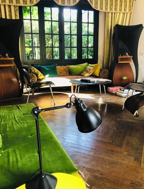 A cozy room with a green sofa, a small round table, and a lamp. - authentique house, ocean first line, private access to the beach (guéthary)