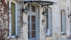 A stone building with a grey door, arched windows, and outdoor seating. - Magnifique Domaine de Caractère en Pleine Nature (GY LES NONAINS)
