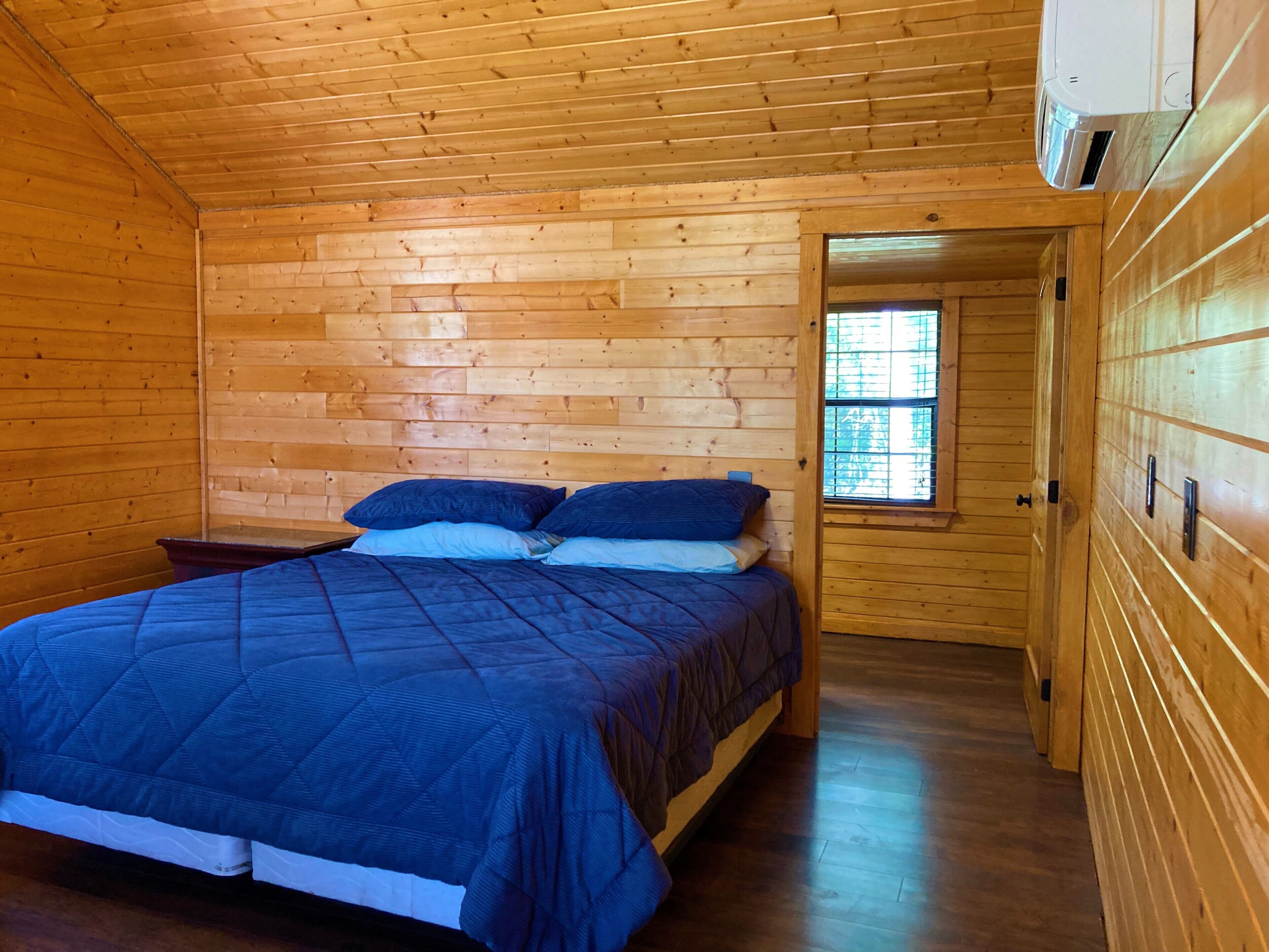 Une chambre dans une cabane en bois, avec un lit, une fenêtre et une porte.