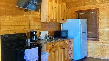 Una cocina con armarios de madera, una estufa negra, un microondas y un refrigerador.