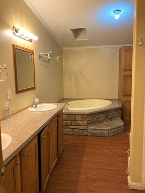 A bathroom with two sinks, a large bathtub, and a stone accent wall. - 1075 Marina Dr (Trinity)
