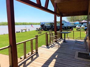 A wooden deck with a view of a lake, picnic tables, and a covered area with RVs and boats. - 1075 Marina Dr (Trinity)