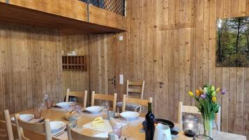 Ein Esszimmer aus Holz mit hoher Decke und Blick ins Freie durch ein Fenster.