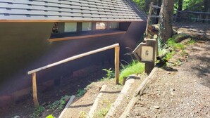 Un bâtiment moderne doté d’un toit en pente, d’une terrasse en bois et d’un chemin de pierre menant à une porte en bois portant le numéro 6.