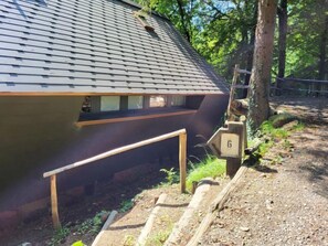 Ein modernes Gebäude mit einem geneigten Dach, einer Holzdiele und einem Steinweg, der zu einem Holztor mit der Nummer 6 führt.