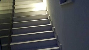 A staircase with white steps and a handrail, leading up to a landing with a window. - Acquamarina (Melendugno)