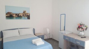 A bedroom with a bed, a desk, a chair, a mirror, and a painting of a coastal scene. - Acquamarina (Melendugno)