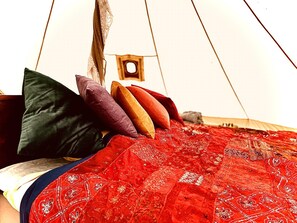 A bed with a red patterned blanket and pillows in various colors. - Tent Delhi, a b&b in a Luxury Glamping Style (Mariefred)