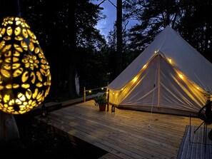 A tent with string lights, a wooden deck, and a potted plant. - Tent Delhi, a b&b in a Luxury Glamping Style (Mariefred)