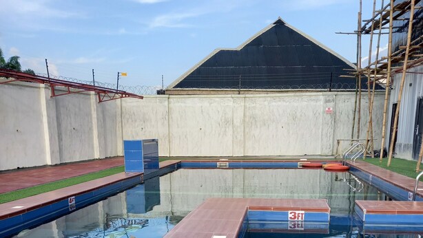 Una piscina con terraza de madera y césped artificial.