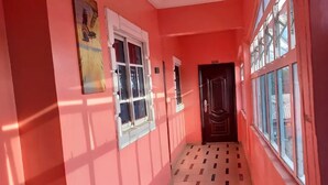 Un pasillo con paredes rosas, piso estampado y ventanas.