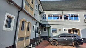 Un edificio de dos pisos con un coche estacionado frente a él.