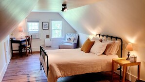 Une chambre mansardée chaleureuse, avec un lit, une table de chevet, une lampe et une chaise.