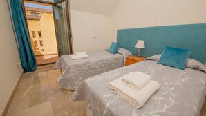 Quarto de hotel com duas camas, vista para o exterior e porta para uma varanda.