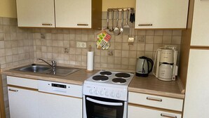 A compact kitchen with a sink, stove, oven, and a coffee maker. - Cozy vacation apartment in the hinterland, ideal for cyclists  (Garz)