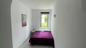 Un dormitorio con cama, ventana y puerta.