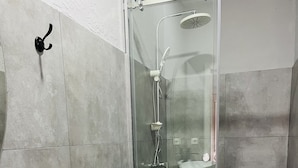 A modern bathroom with a glass-enclosed shower, a white sink, and a toilet.