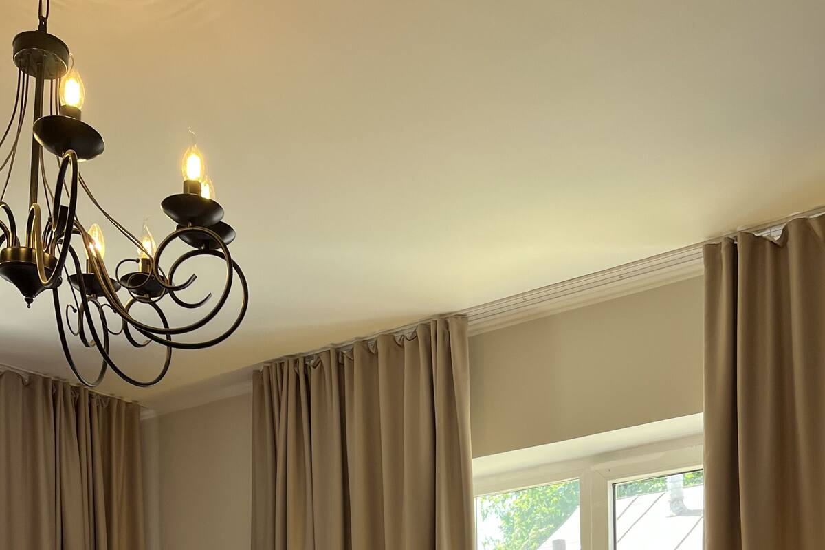 Un lit bien fait, avec du linge de lit blanc et des oreillers, une tête de lit en bois et un lustre au-dessus.