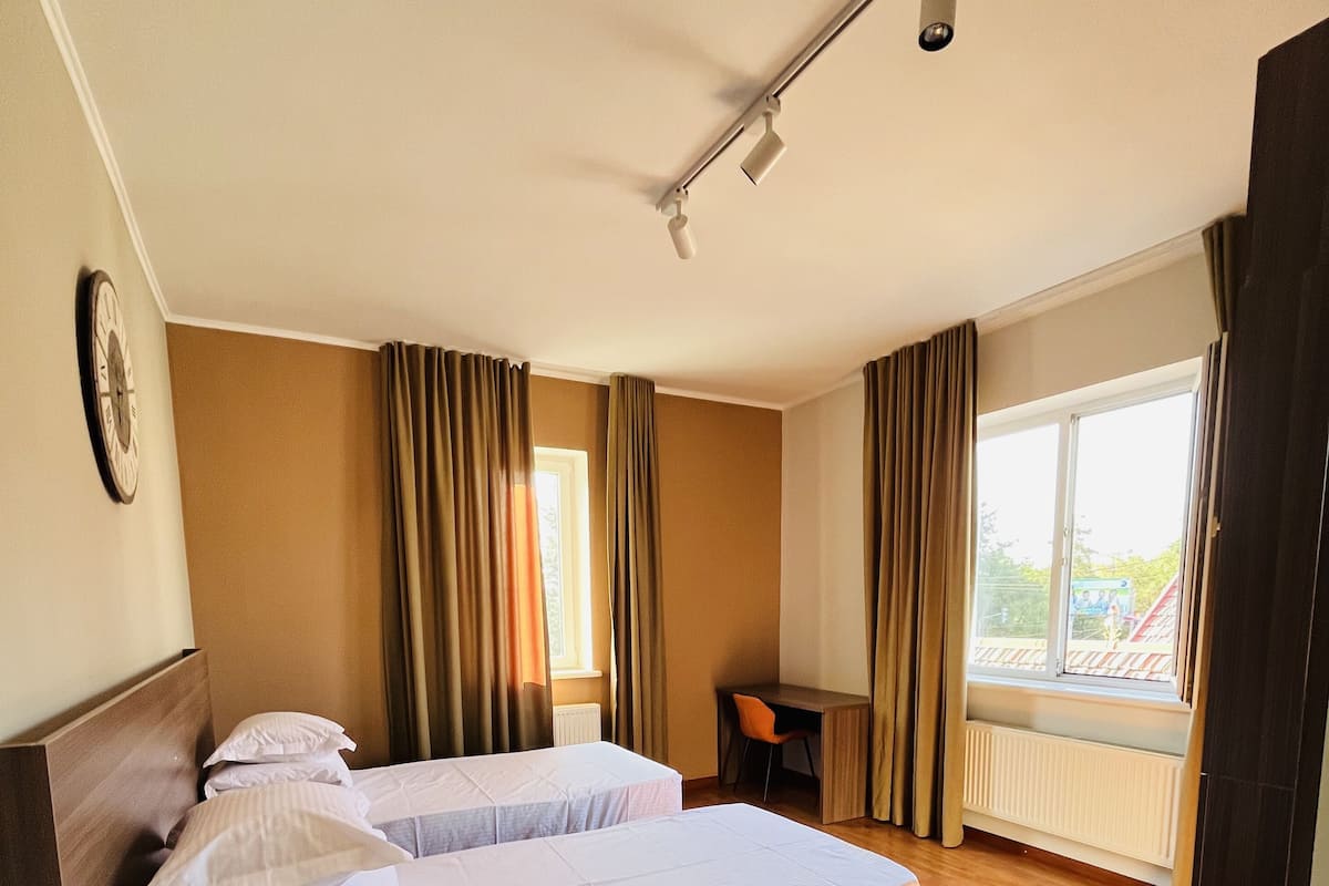 Une chambre d’hôtel avec deux lits, un bureau et une vue sur l’extérieur.