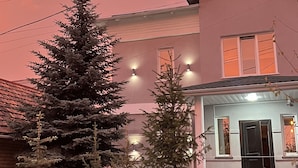 A house with a sloped roof, a front porch, and a driveway leading to a parked car.