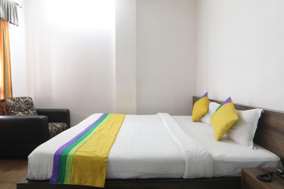 A hotel room with a bed, a chair, and a nightstand.