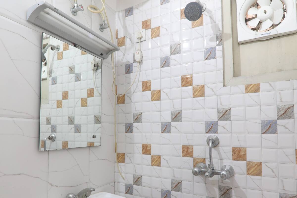 A bathroom with a white sink, a mirror, a shower with a handheld showerhead, and a wall-mounted fan.