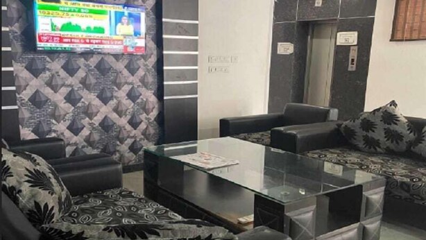 Un vestíbulo moderno con un papel tapiz estampado, un televisor de pantalla plana y un área de descanso con cojines decorativos.