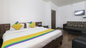 Una habitación de hotel con cama, sofá, televisión y escritorio.
