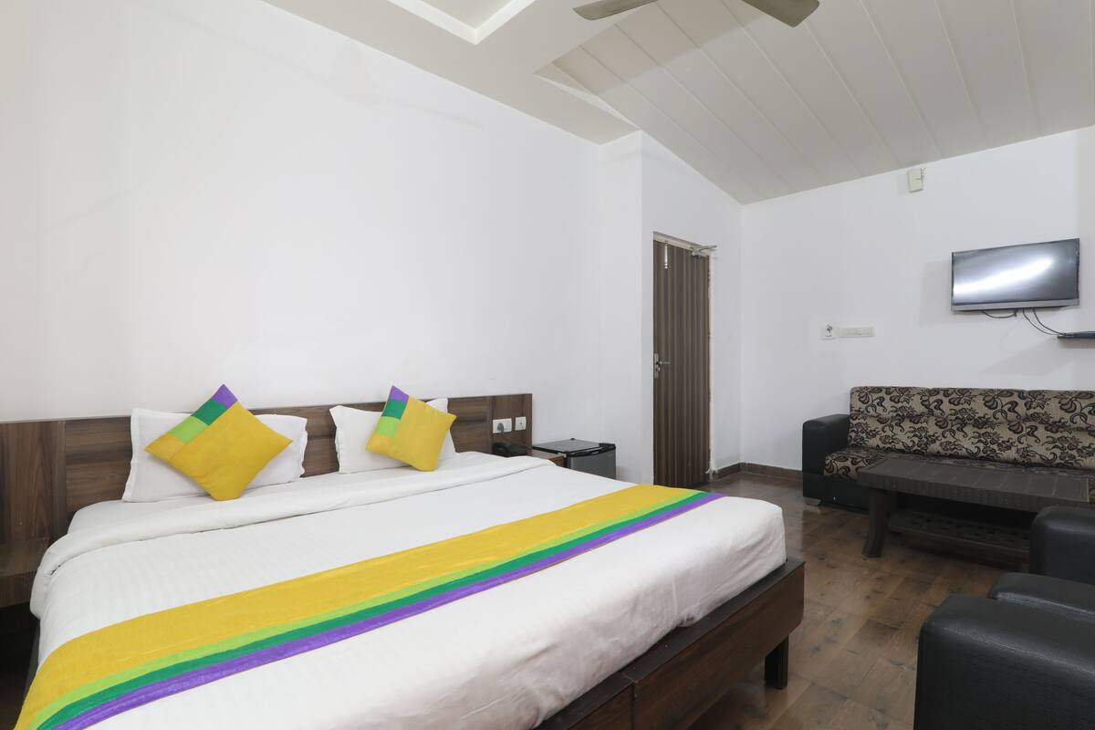 A hotel room with a bed, a sofa, a television, and a desk.