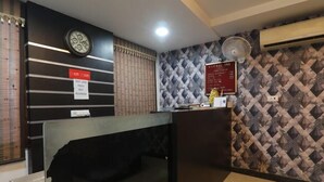 Una zona de recepción con un reloj, un cartel que indica que no se permite comer y una pared con diseño.
