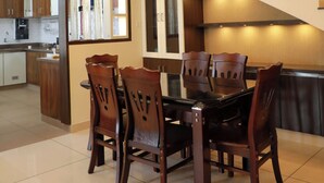 Ruokailutila, jossa on pöytä ja tuoleja, portaikko ja taustalla keittiö.