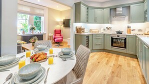 Une cuisine moderne avec des meubles de couleur verte, un coin repas doté d’une table ronde et une chaise rouge.