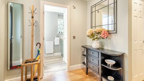 Un couloir avec un miroir, un porte-manteau et une console sur laquelle est posé un vase de fleurs.