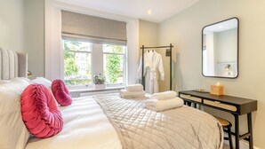 Une chambre d’hôtel comprenant un lit, une fenêtre, un miroir, un bureau et un porte-peignoir.