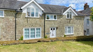 A stone house with a white door, large windows, and a stone wall.