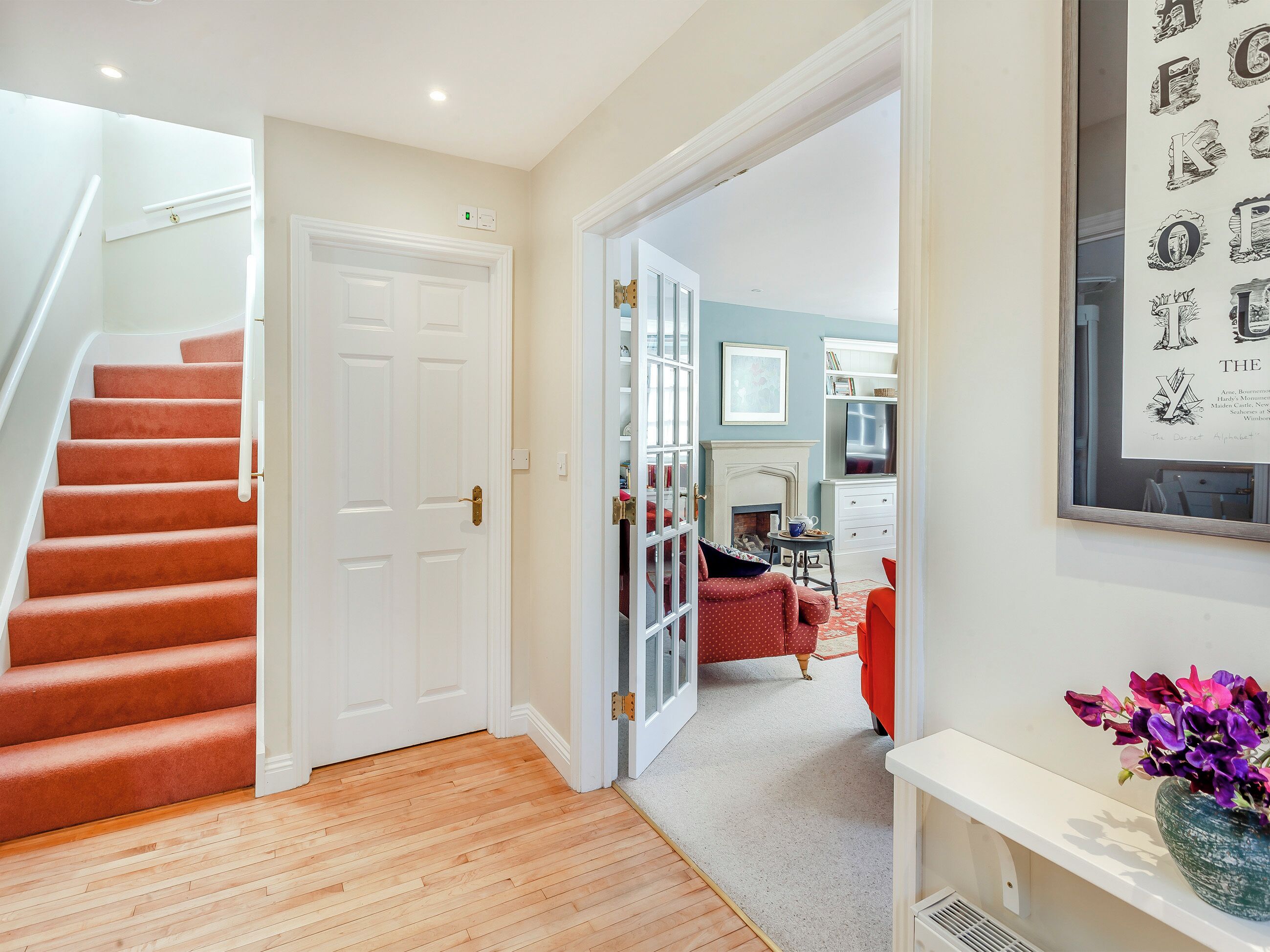 A staircase leading to a room with a fireplace, a dining area, and a hallway with a framed alphabet artwork.
