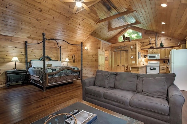 Interior acogedor de una cabaña con una cama con dosel, un sofá, zona de comedor y cocina.