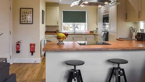 A modern kitchen with a central island, stainless steel appliances, and a window providing natural light. - 3 bedroom accommodation in Helmsley (Helmsley)