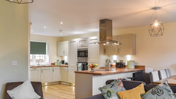 A modern kitchen with a central island, a dining area with a sofa and chairs, and a living room with a sofa and a coffee table. - 3 bedroom accommodation in Helmsley (Helmsley)