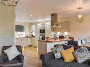 A modern kitchen with a central island, built-in appliances, and a dining area with a sofa and chairs.