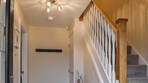 A staircase with a wooden handrail and a white balustrade, leading to a landing with a light fixture and a vase with flowers. - 3 bedroom accommodation in Helmsley (Helmsley)