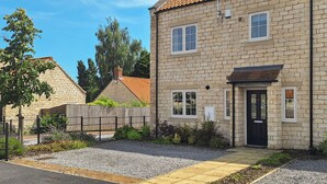 A stone house with a tiled roof, a black door, and a gravel driveway. - 3 bedroom accommodation in Helmsley (Helmsley)