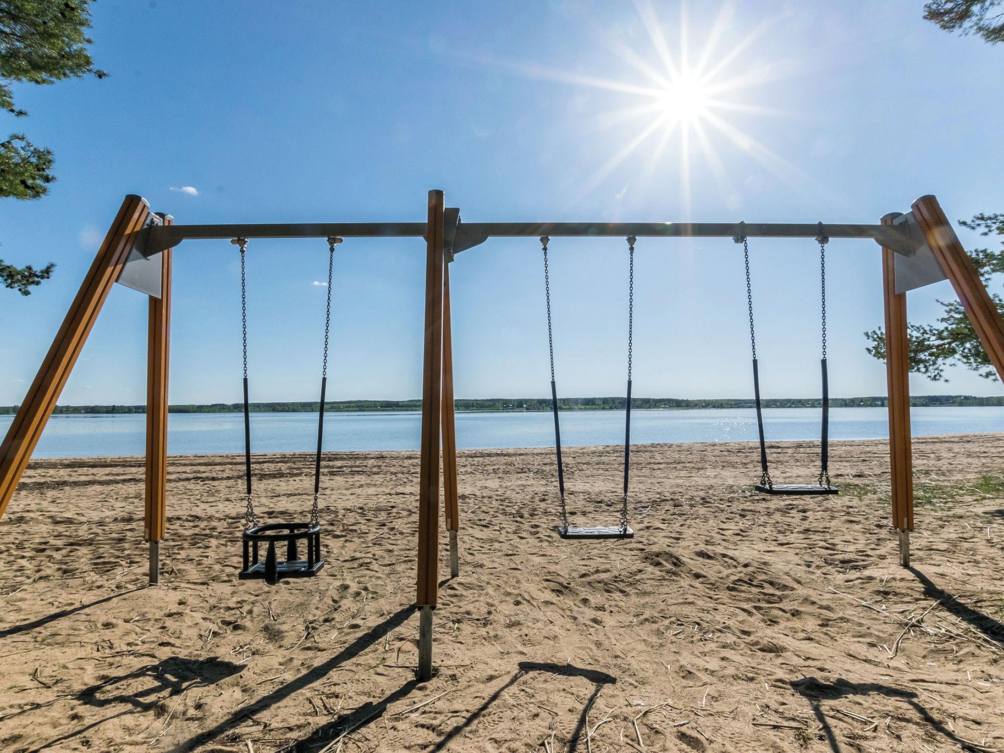 Une balançoire installée sur la plage, offrant une vue dégagée sur le lac et le ciel.