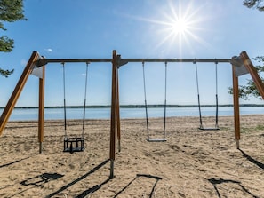 A beach swing set with a clear view of the lake and sky.