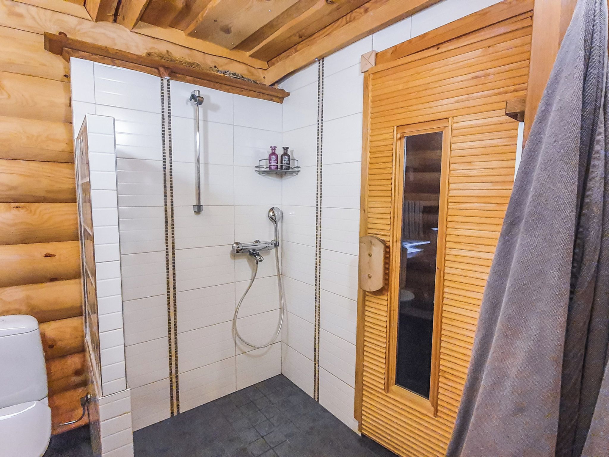 Ein Badezimmer mit Holztür, weißen Fliesen und einer Duschkabine.