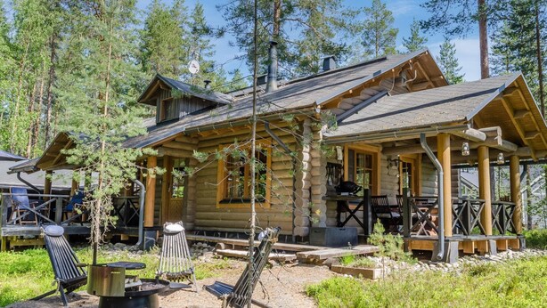A rustic log cabin with a covered porch, outdoor seating, and a fire pit.